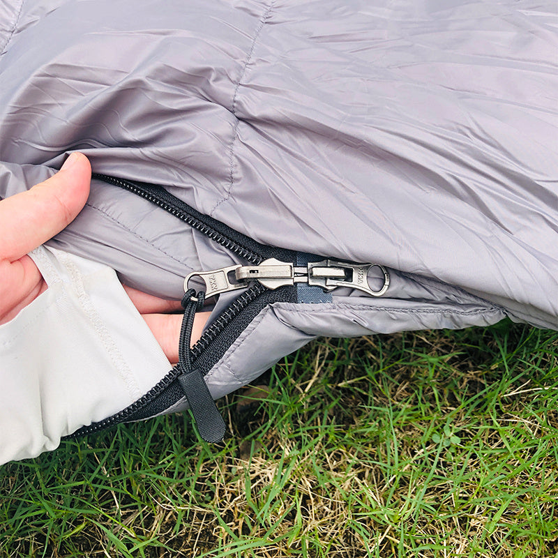 Close-up of Kamperbox Goose Down Sleeping Bag zipper on grass, highlighting quality material and design.